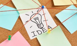 painted light bulb with word idea and colored blank notes on cork board