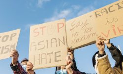 Group of demonstrators protest on the street for equal rights - Asian people demonstrators wearing face masks during stop asian hate campaign - Focus on banners