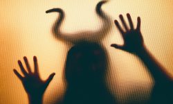 Creepy figure with horns in the dark, behind the window. Halloween background