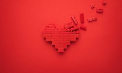 Red falling apart heart symbol made of plastic building blocks. Flat lay image of breaking down like button on red background. Minimalist photo of stylized dissolving love symbol.