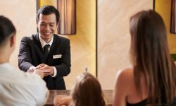 Smiling hotel receptionist asking guests to give him passports